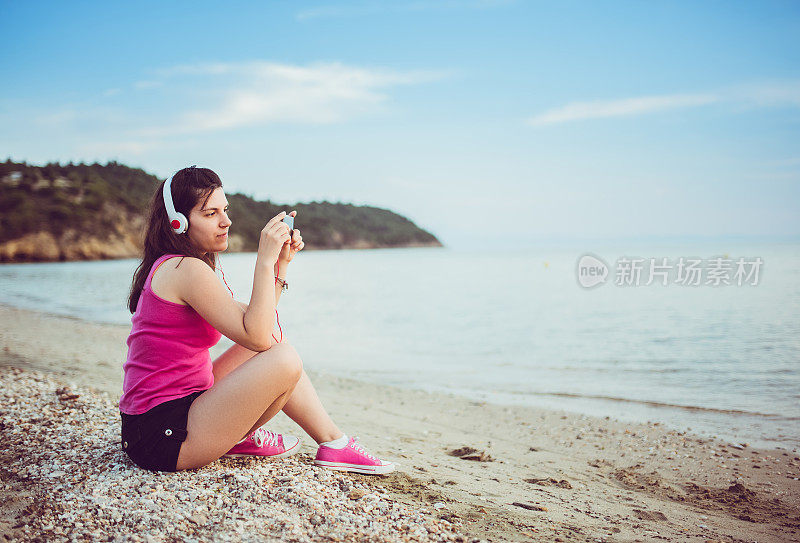 年轻女子和音乐在海滩上