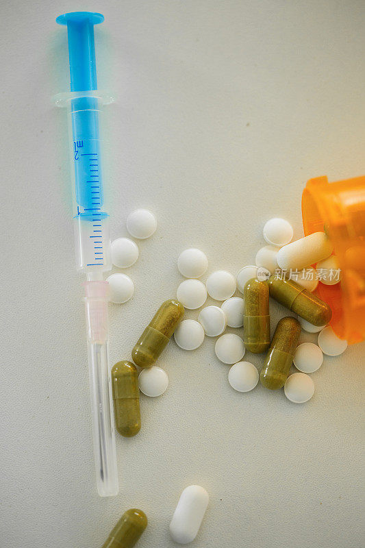 注射器旁边有一组不同的药片和胶囊