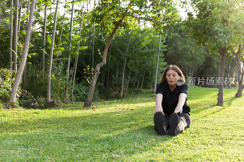 成熟的女人在公园伸展身体