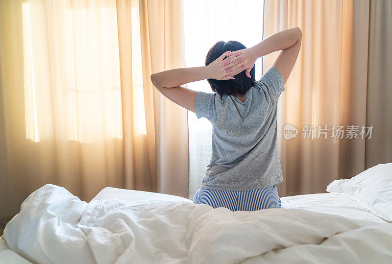 女人醒来后在床上伸懒腰，用手抄空间