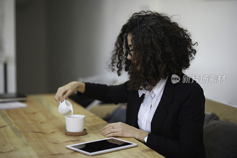 一位女商人正在往咖啡里加牛奶