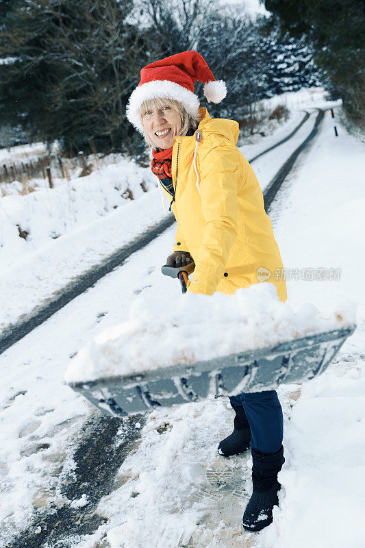 老妇人正在用雪铲清理积雪