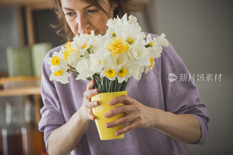 女人一边欣赏一边闻着一束水仙花