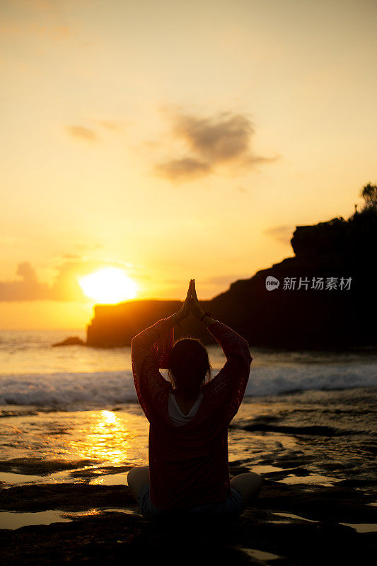 日落时分坐在海边的亚洲女人