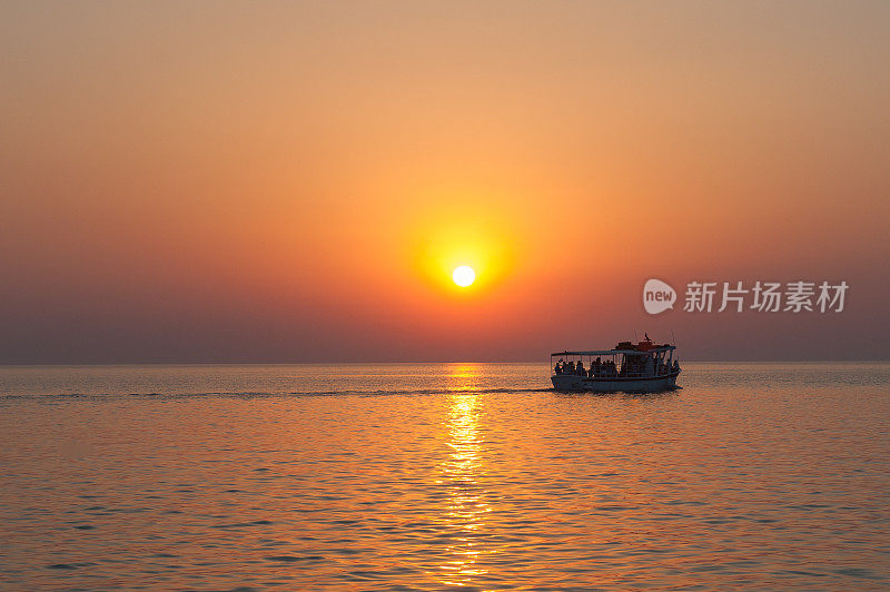 游艇、小舟、小舟在地平线上映出美丽的晚霞剪影，夕阳炙热。游轮