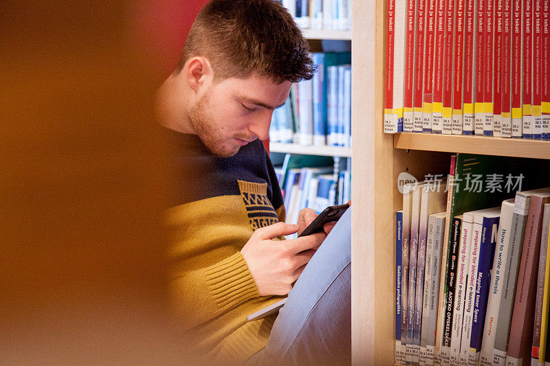 青年学生在图书馆使用手机