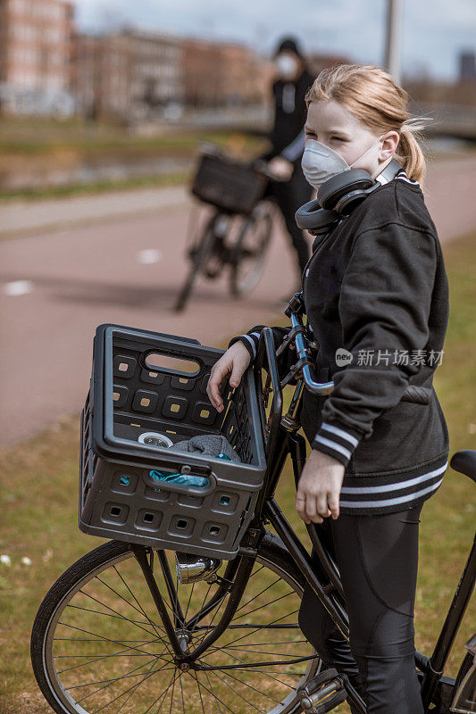 年轻女孩骑自行车时戴着口罩