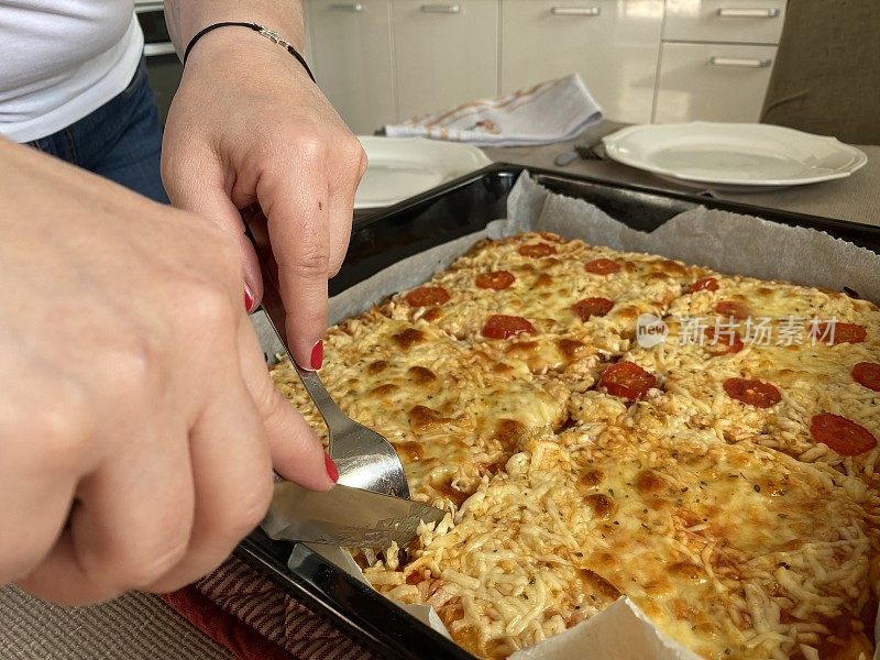 近距离的手切割一个新烤的自制披萨