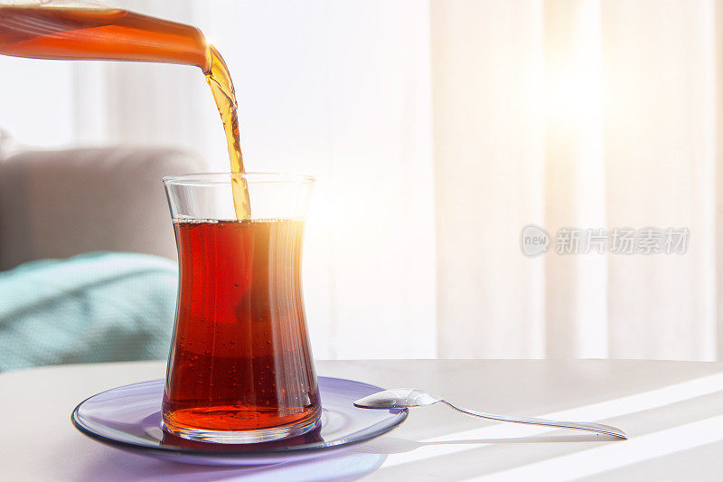 红茶，茶从茶壶里倒出来，茶杯放在咖啡桌上