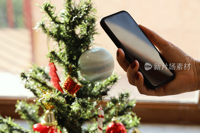 手持手机与圣诞树
