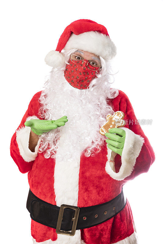 圣诞老人戴着面具和橡胶手套拿着带面具的姜饼饼干