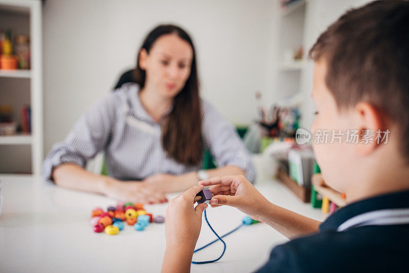 学龄前男孩和他的职业治疗师一起做项链