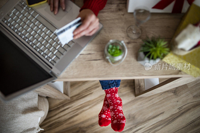 女人用信用卡在家里买新年的礼物-圣诞购物-一个年轻女人在网上买礼物的特写