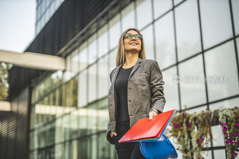 女商人拿着文件和头盔在户外