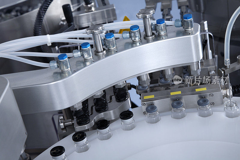 在生产的玻璃瓶托盘上有一个自动液体分配器，用于灌装抗菌病毒药物、抗生素和疫苗的流水线