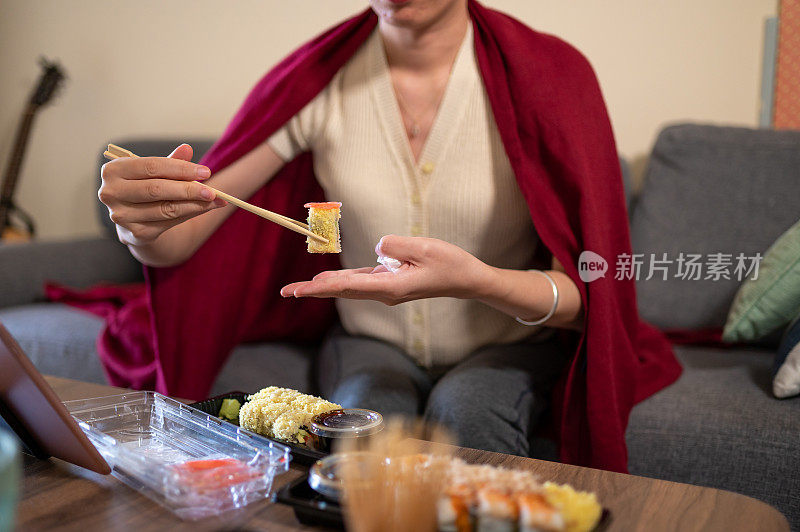 在家吃带酱料的塑料包装寿司卷的妇女