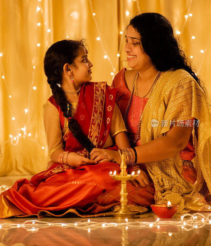年轻的印度女孩和她的母亲拿着排灯节油灯