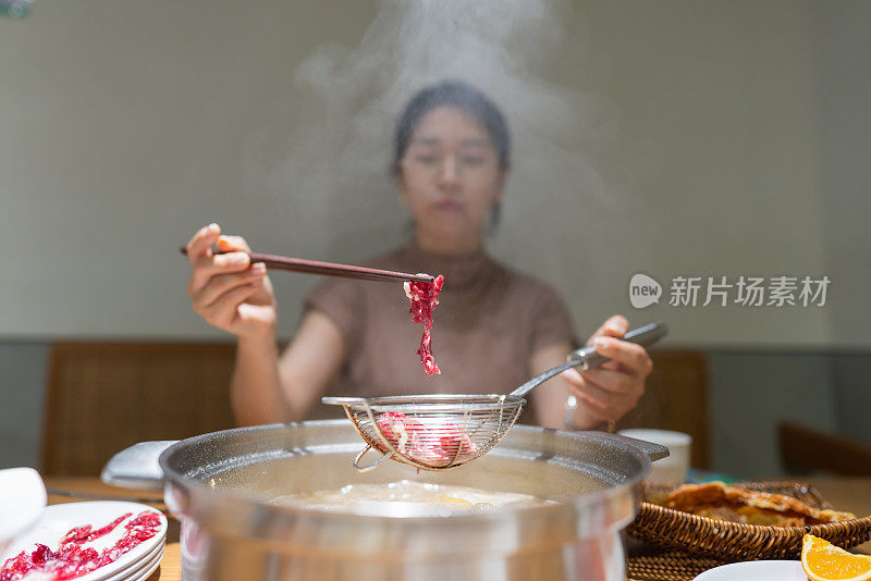 亚洲妇女用筷子夹牛肉