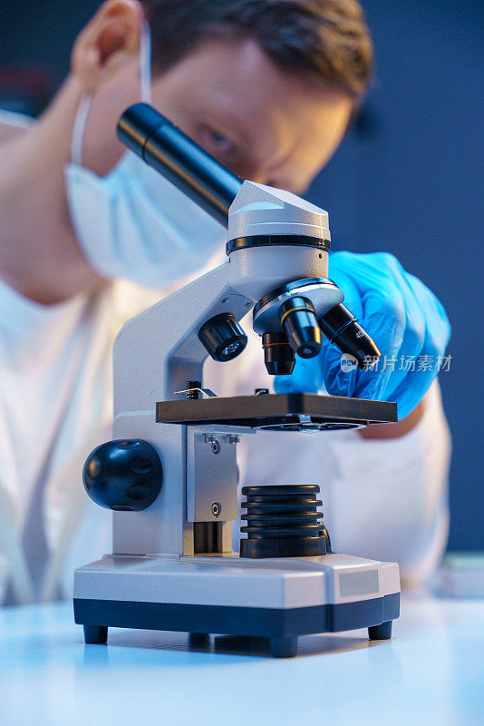 一位科学家将显微镜载玻片放入显微镜中