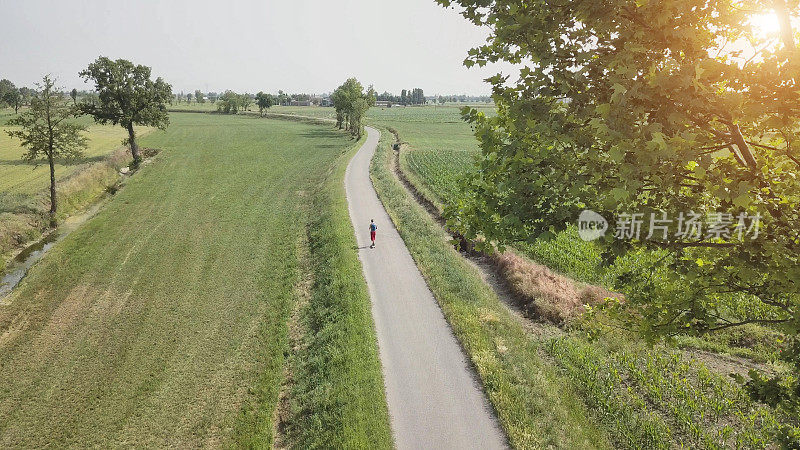 春天乡间小路上的长板上的成熟男人(鸟瞰图)