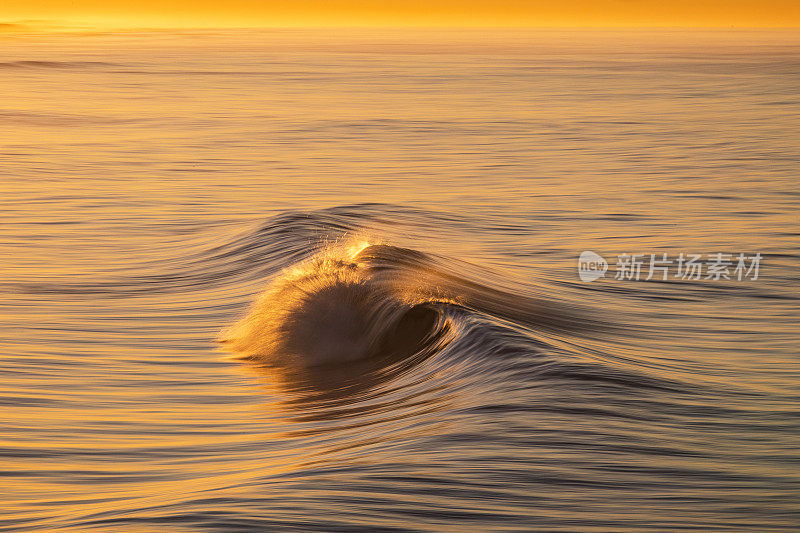 金色的海浪在沙滩上反射出明亮的金色日出