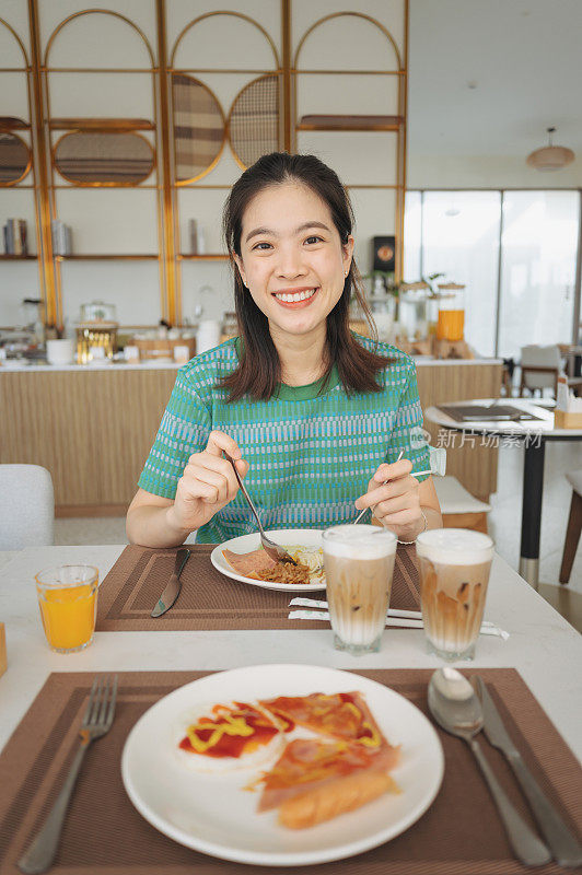 年轻快乐的亚洲女人在餐厅吃早午餐