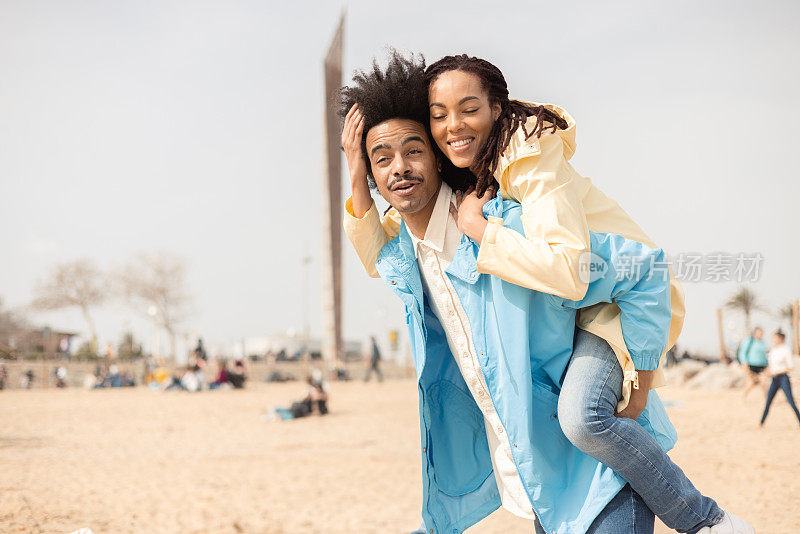 一对快乐的非裔美国夫妇在海滩上一起享受的肖像