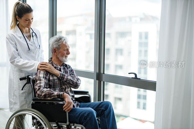 残疾成年男子和他的照顾者在家里透过窗户看。