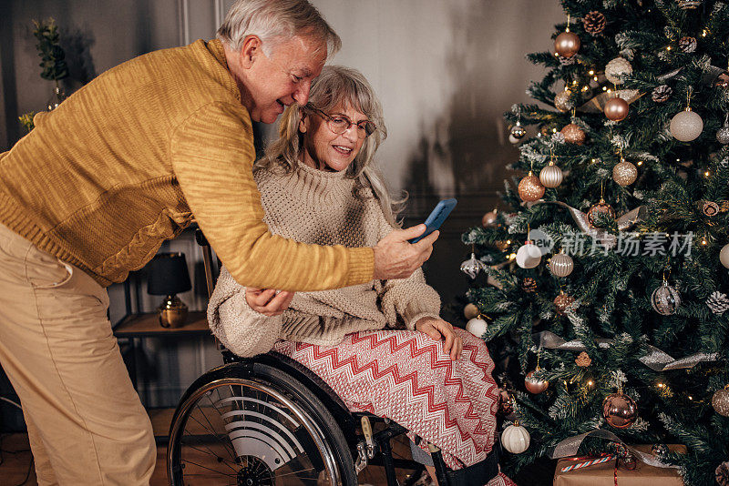 老夫妇在家里装饰圣诞树时拍照