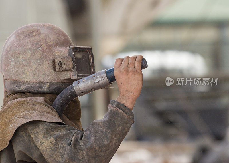 一名工人正在对锈蚀的船体进行喷砂处理