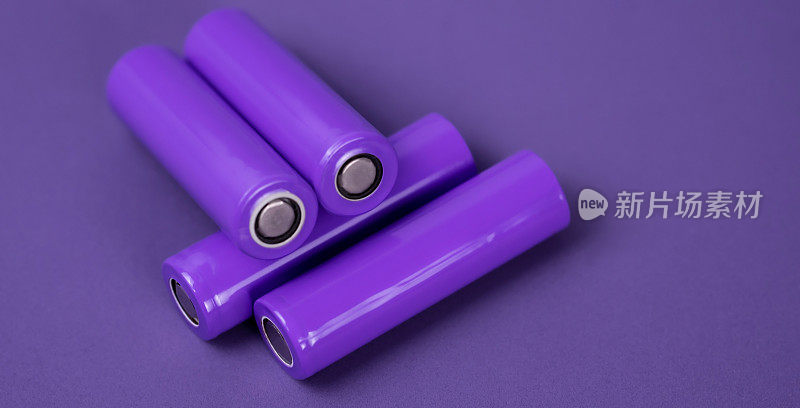 电池。圆柱形电池，18650型，紫色背景。用于电器和设备的可充电锂离子电池。