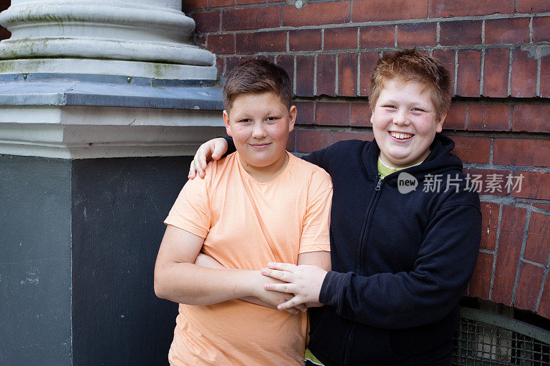 友谊:两个超重的十几岁的男孩站在他们的学校前面