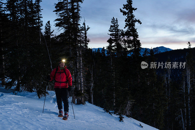 人滑雪旅行在黄昏与头灯