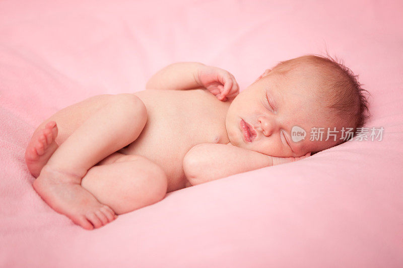 新生女婴安静地睡在粉红色的毯子上