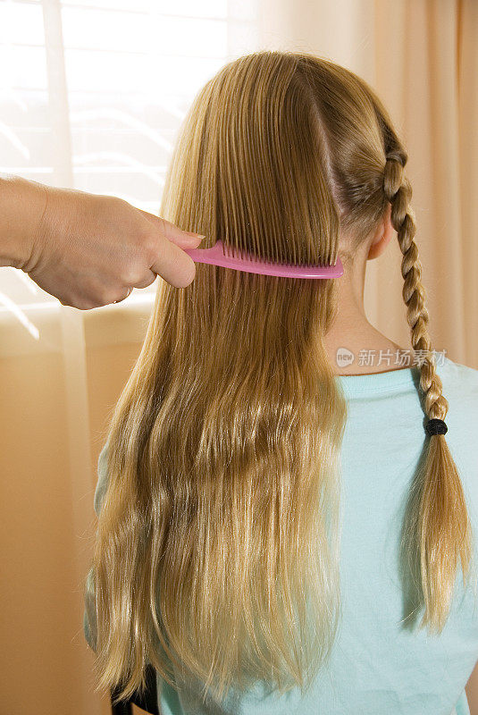 小女孩梳着她的长发，编着辫子