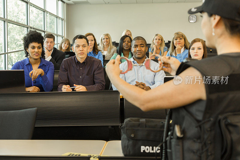 法律:女警察在教室里和警察学员说话。手铐。