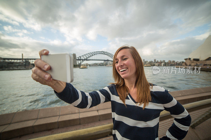 一名女子在悉尼港用手机自拍