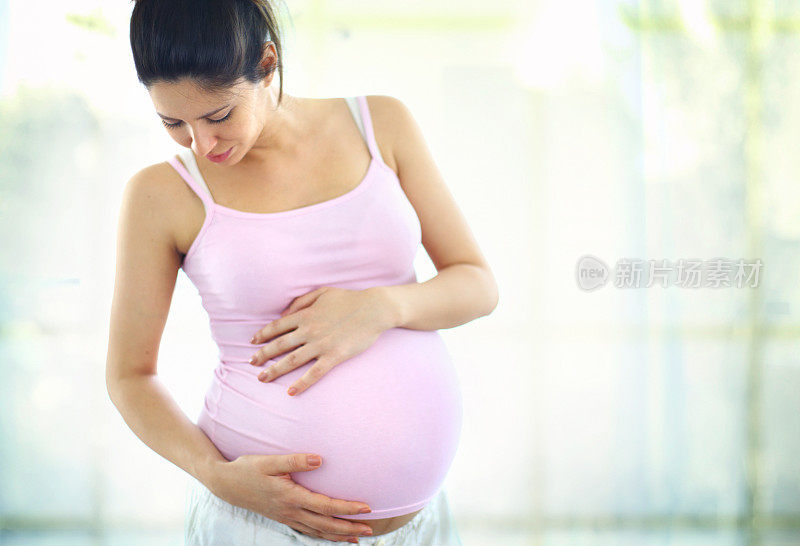 孕妇抚摸着自己的肚子。
