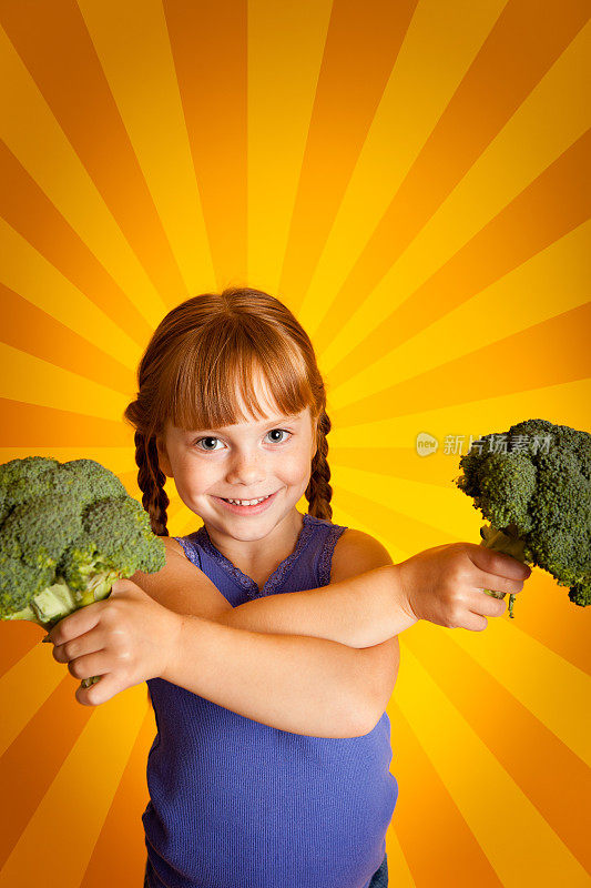 可爱的小女孩抱着花椰菜，橙色和黄色的背景
