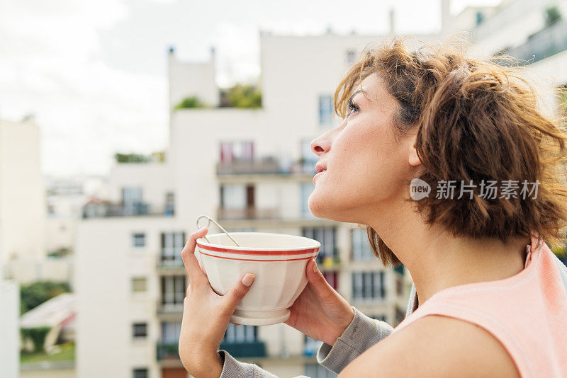 年轻女子在城市阳台上享用早茶。