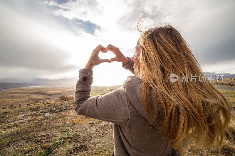 一个女人在自然界做了心形的手指架