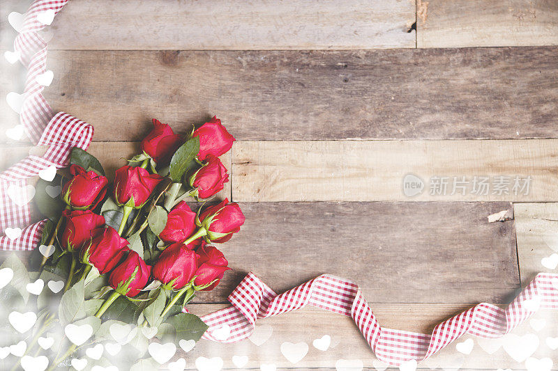 情人节快乐!红玫瑰花束，丝带放在质朴的桌上。