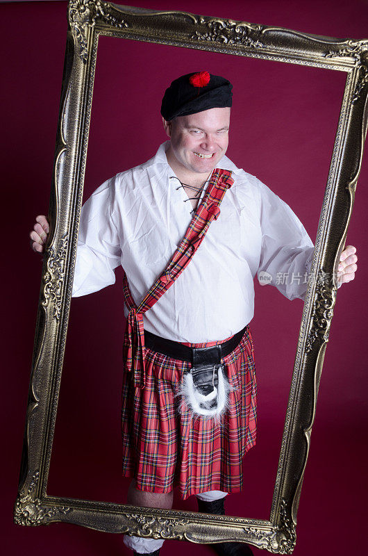 穿着苏格兰服装的男人透过画框邪恶地笑着。