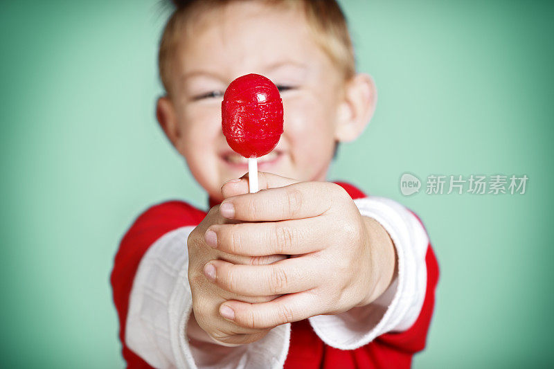 小男孩拿着红色的棒棒糖对着镜头