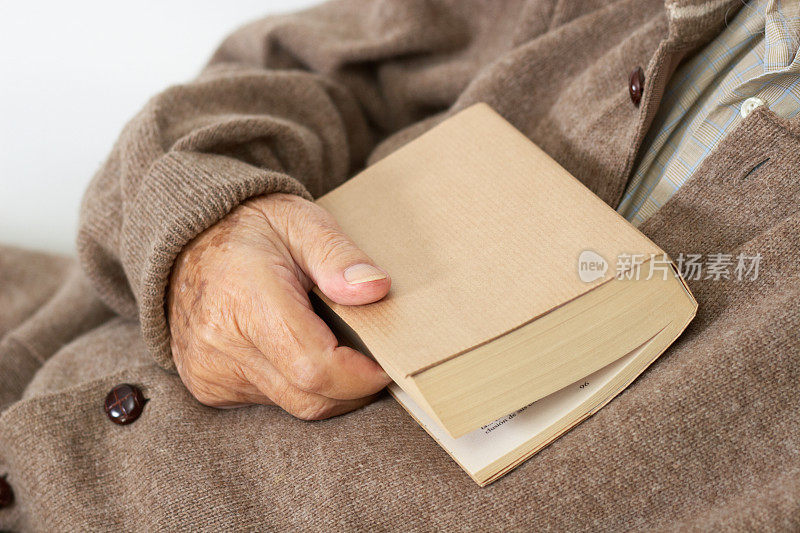 老人的手拿着一本书。