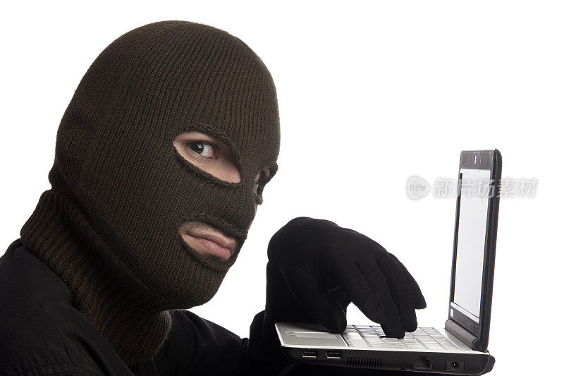 电脑黑客戴着雪面罩和手套使用笔记本电脑键盘