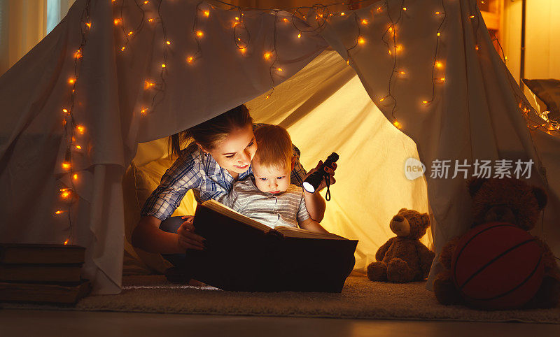 母亲和孩子在睡觉前拿着一本书和一个手电筒