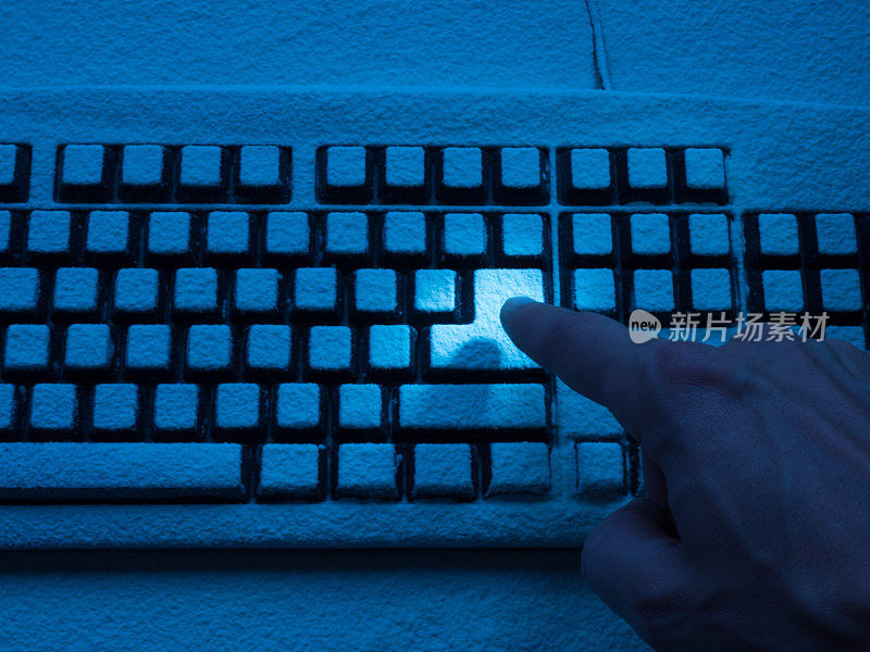 人的食指按下输入键，键盘上覆盖着蓝色的霓虹灯