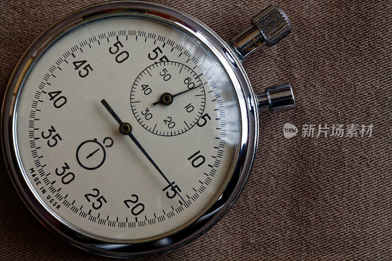 秒表上的米色牛仔裤背景，值测量时间，旧时钟箭头分秒精确计时器记录