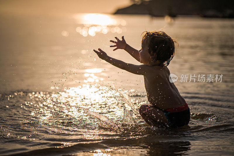 快乐的小男孩玩的时候，在浅水的海。